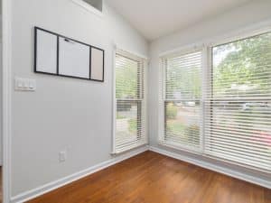 Do Venetian blinds block out light? Sunlit room with white Venetian blinds filtering natural daylight through large windows.