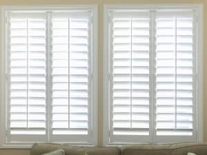 Full-length white shutters on a window across a modern lounge room wall