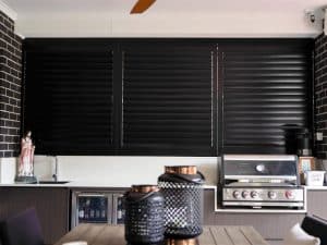 Black plantation shutters in alfresco kitchen, showing modern finish suitable for window shutter replacement projects.