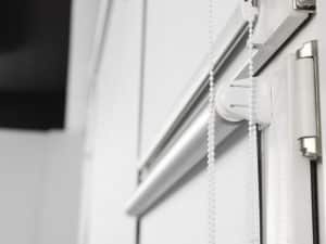 Chain-operated mechanism on door reveals compact roller blinds sizes for narrow window frames