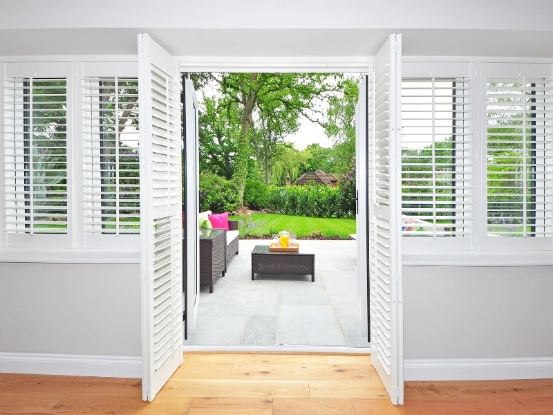 White timber plantation shutters framing an open doorway, representing the best material for plantation shutters in homes.