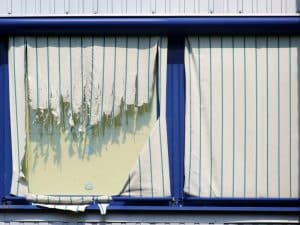 Worn vertical blinds on Sydney home window replaced by plantation shutters Sydney for durability