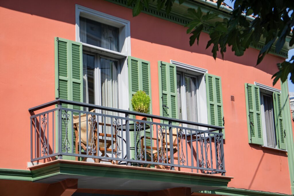 A view of a classic home facade with a charming balcony and green shutters.